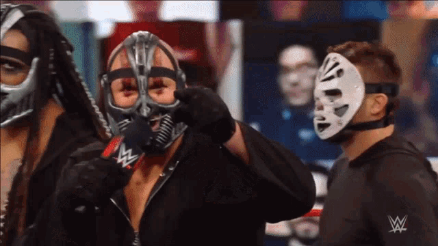 a man wearing a mask talks into a microphone with a w logo on his back
