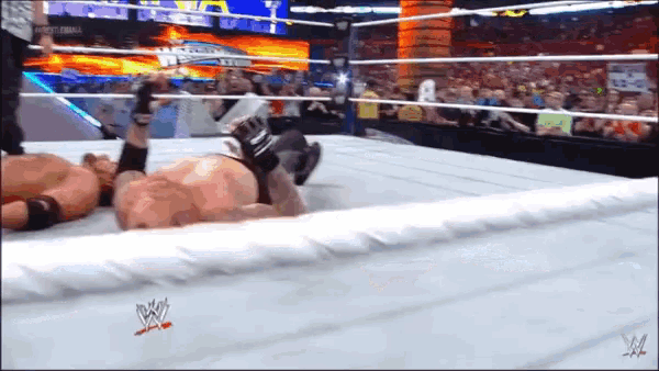 a wrestler is laying on the ground in a wrestling ring with a wwe logo on the floor
