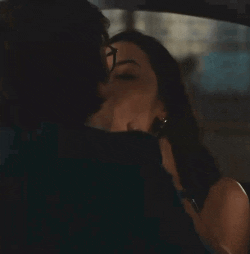 a man and a woman are kissing in the back of a car .