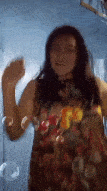 a woman in a floral dress is dancing with soap bubbles in the background