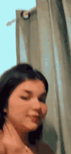 a woman is standing in front of a curtain in a room and looking at the camera .
