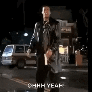 a man in a trench coat is standing on a street with his arms outstretched and says `` ohh yeah '' .