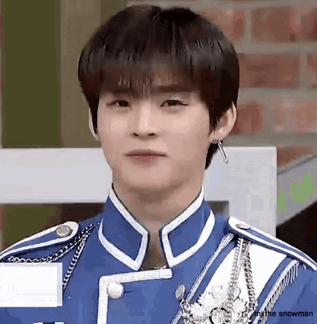 a young man in a blue and white uniform is looking at the camera and wearing earrings .