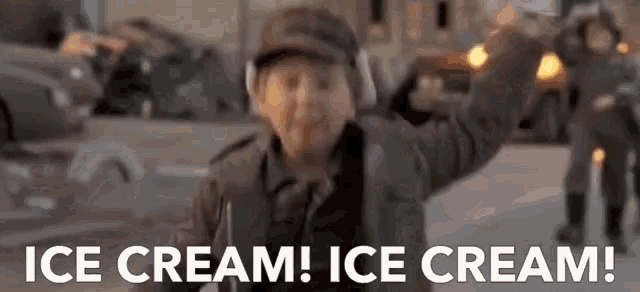 a man in a hat is standing on a street holding up his fist and screaming ice cream !