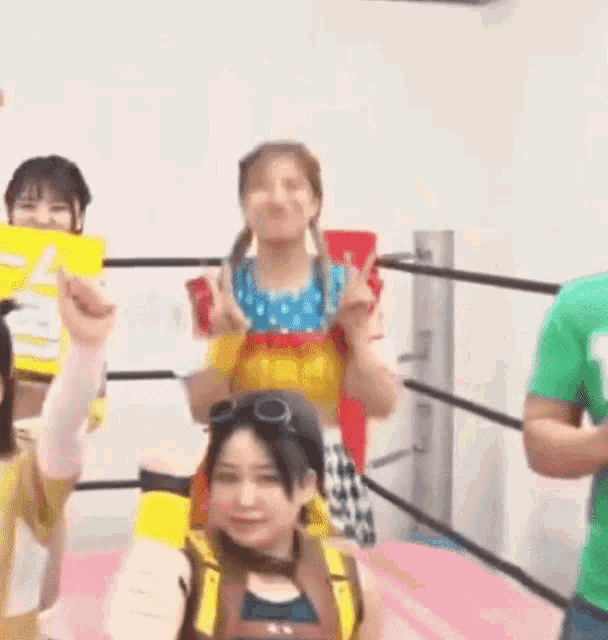 a group of young women are standing in a wrestling ring holding signs .