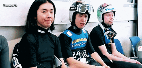 a man wearing a helmet that says uvex sits next to another man