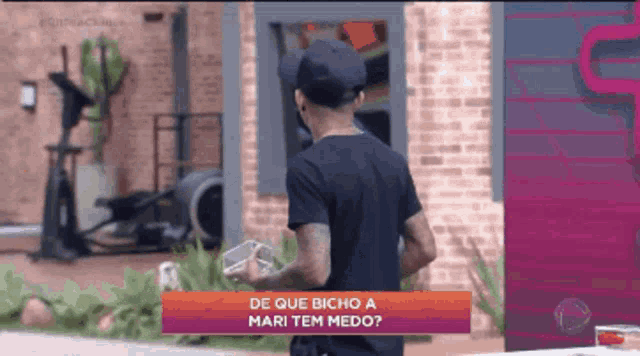 a man in a black shirt is standing in front of a sign that says de que bicho a mari tem medo