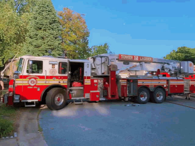 a red and white tower 12 ladder fire truck parked in a driveway