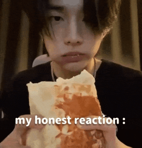 a young man is eating a sandwich with the words `` my honest reaction '' written on it .