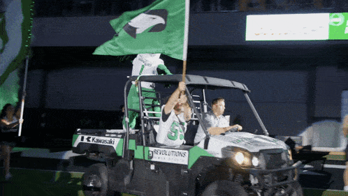 a man in a kawasaki vehicle holds a flag