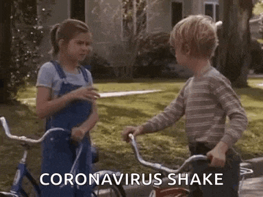 a boy and a girl are shaking hands while riding bicycles on a sidewalk .