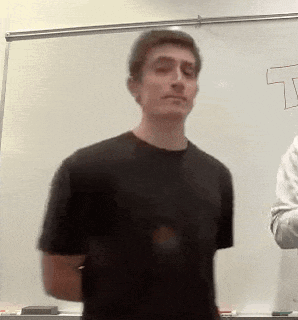 a man in a black shirt is standing in front of a white board with the letter t drawn on it