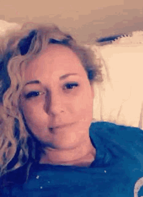 a woman is laying on a bed with her head on a pillow .