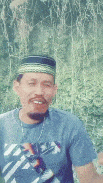 a man with a beard wearing a hat and a blue shirt with palm trees on it