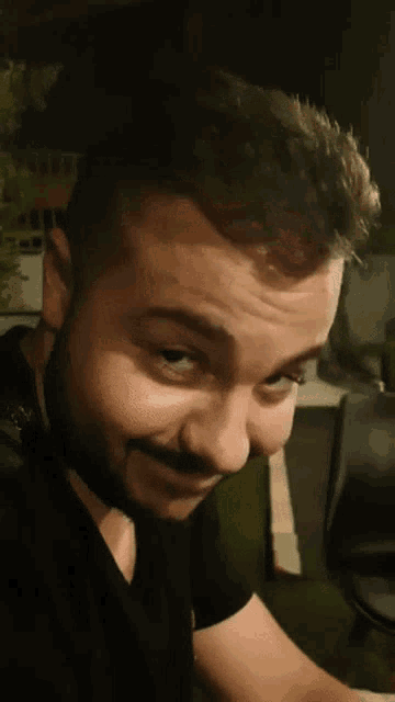 a man with a beard is wearing a black shirt with the letter g on it