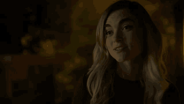 a woman with blonde hair is smiling in a dark room