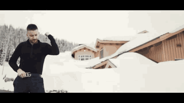 a man wearing a gucci belt stands in front of a snow covered house