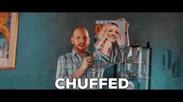 a man in a plaid shirt is holding a picture of a woman and the word chuffed is above him .