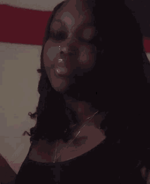 a close up of a woman 's face with long hair and a necklace .