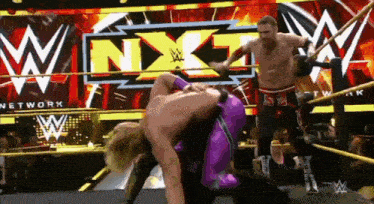two wrestlers are wrestling in front of a sign that says nxt