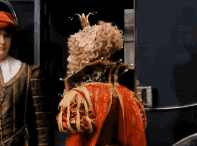 a man in a costume with a crown on his head is standing next to another man in a costume .