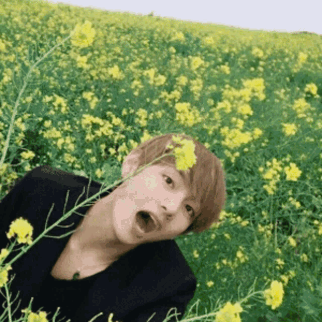 a person is standing in a field of yellow flowers with their mouth open