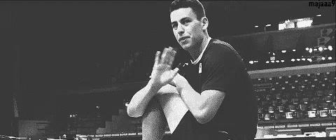 a black and white photo of a man clapping his hands in a stadium .
