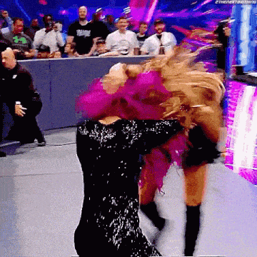 a woman in a black and pink dress is dancing on a stage .