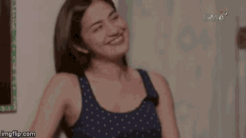 a woman in a blue tank top is laughing with her eyes closed