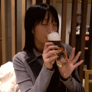 a woman drinking a glass of beer with a ring on her finger