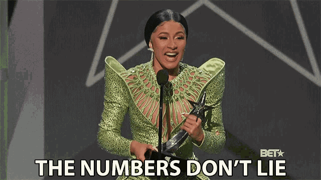 a woman in a green dress is holding a trophy and says the numbers don 't lie
