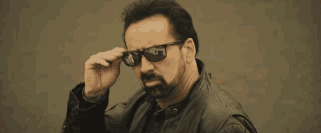 a man with a beard wearing sunglasses and a black jacket