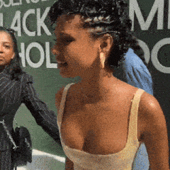 a woman with curly hair is standing in front of a sign that says ' black hol ' on it