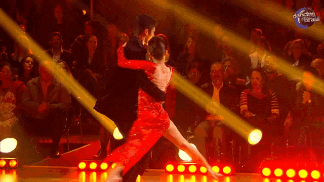 a man and a woman are dancing in front of a crowd that is watching dancing with the stars