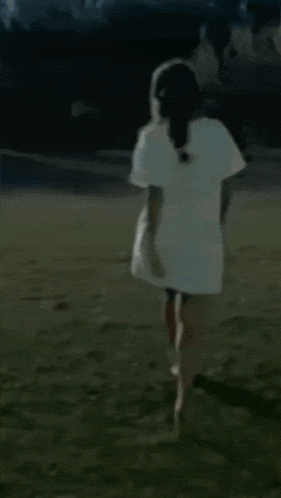 a woman in a white dress is walking barefoot in a field
