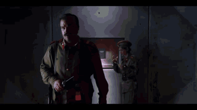 a man in a military uniform holds a gun in his hand