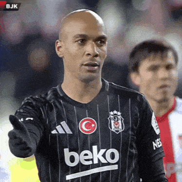 a soccer player wearing a black beko jersey is pointing