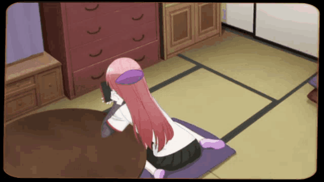 a girl with pink hair is sitting on a purple pillow in a room