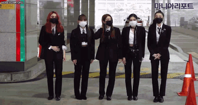 a group of women wearing suits and masks are standing in a parking garage