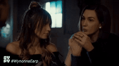 two women are covering their mouths with their hands .