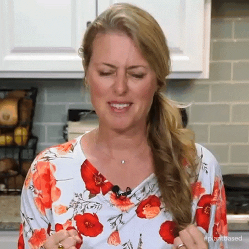 a woman in a floral shirt is making a funny face while holding her hair .