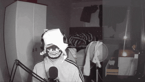 a person with a skull mask on their face stands in front of a microphone