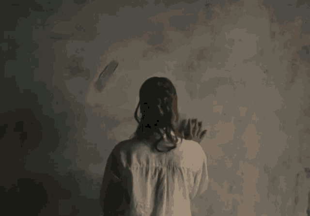 a woman in a white shirt is standing in front of a white wall
