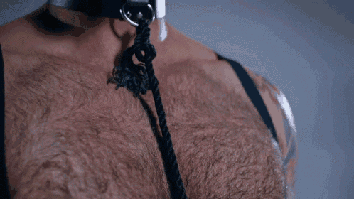 a close up of a man 's chest with a black rope around his neck