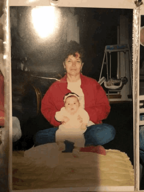 a woman in a red jacket holds a baby