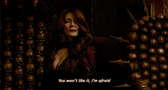 a woman stands in front of a wall of skulls and says you won 't like it