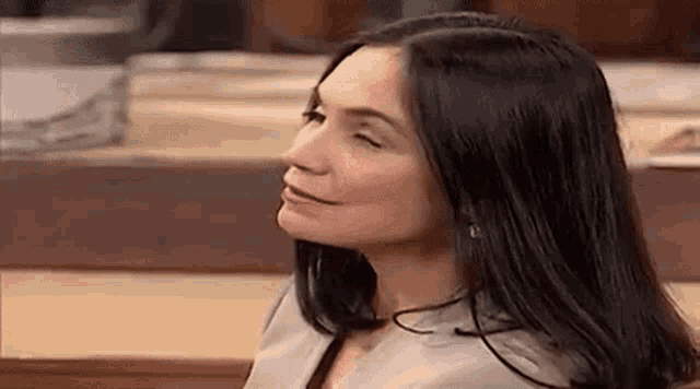 a woman with black hair is sitting at a table with her eyes closed .