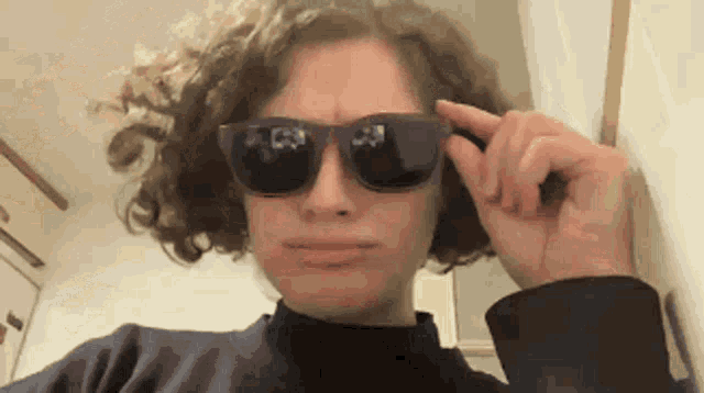 a woman with curly hair is wearing sunglasses