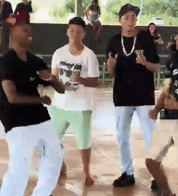 a group of men are dancing in a room with a woman sitting on a bench in the background