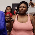 a woman in a pink tank top is standing in front of a crowd of people .